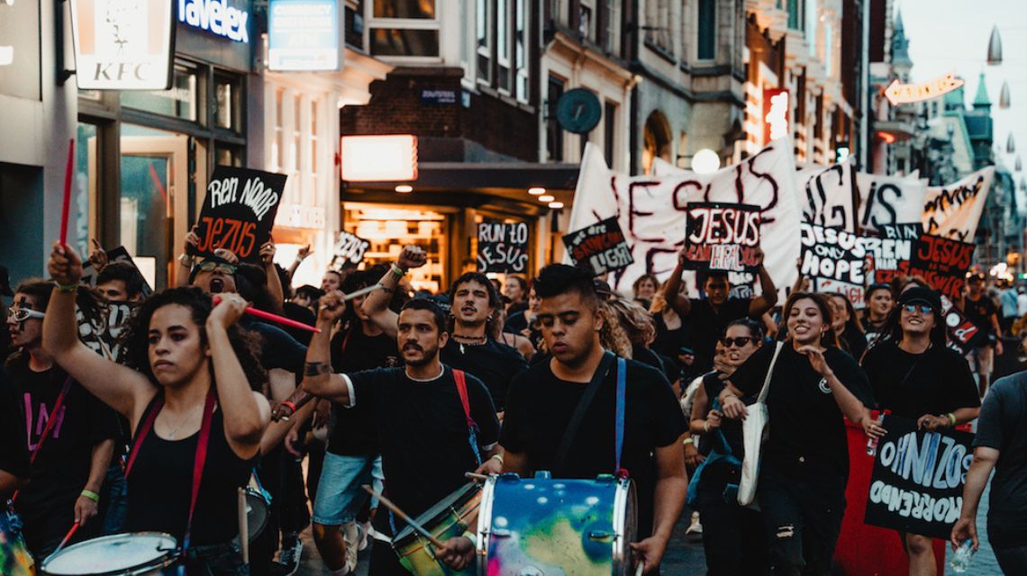 Students descend on the Amsterdam streets with a Jesus protest.